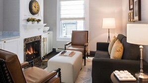 A living room with a fireplace, a clock, a sofa, and a lamp. - Inn At Union Square (San Francisco)