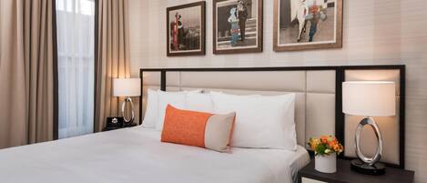 Una habitación de hotel con una cama grande, dos mesitas de noche y tres cuadros enmarcados en la pared.