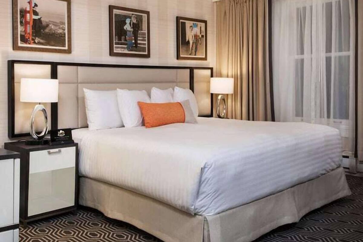 A hotel room with a bed, nightstands, a ceiling fan, and framed pictures on the wall.