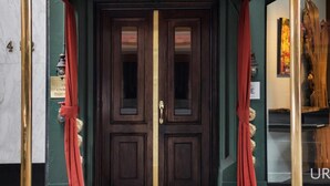 A red sign for The Inn at Union Square, 440 Post Street, with a dark wooden door and green walls. - Inn At Union Square (San Francisco)
