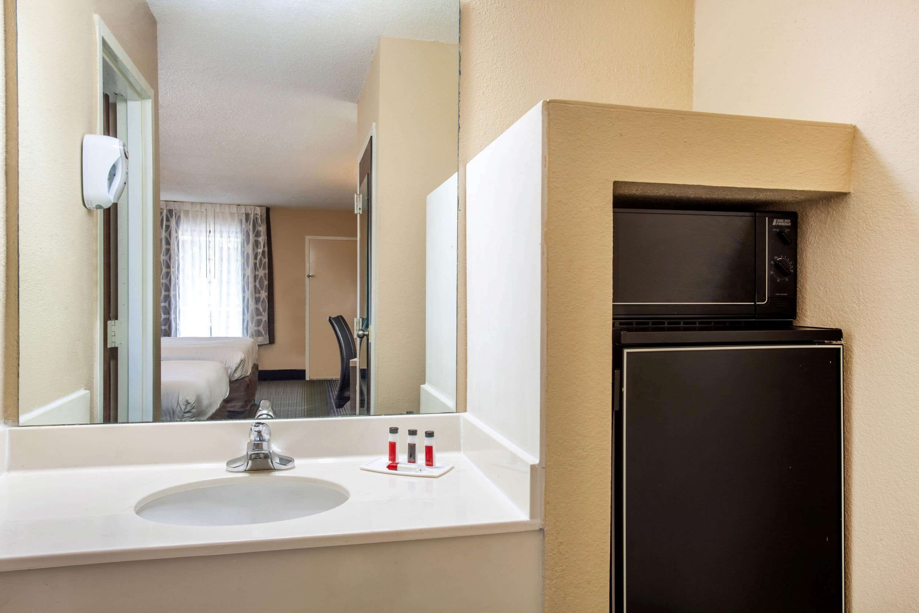 Een hotelbadkamer met een wastafel, spiegel en een magnetron.