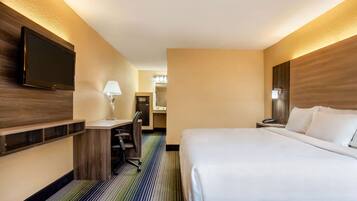 A hotel room with a bed, desk, chair, TV, and a mirror.