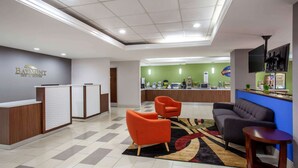 Un vestíbulo de hotel con mostrador de recepción, una pared verde, zona de bar y asientos.