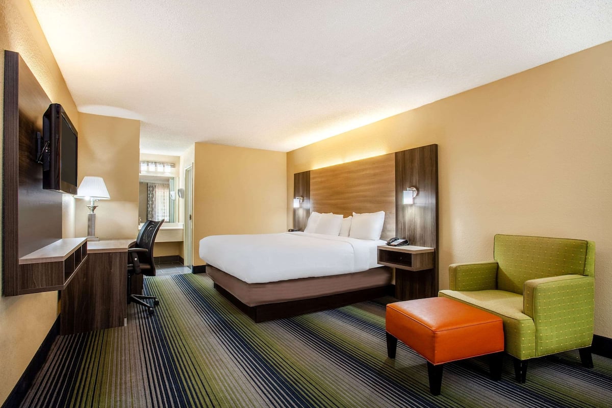 Ein Hotelzimmer mit einem Bett, einem Schreibtisch, einem Stuhl, einem Fernseher und einer Lampe.