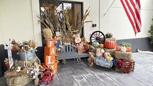 A decorated front porch with pumpkins, hay bales, and a scarecrow. - Clarion Inn Nashua (Nashua)