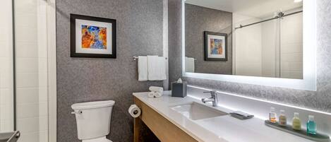 A modern bathroom with a white toilet, a large mirror, and a vanity with a sink and countertop.