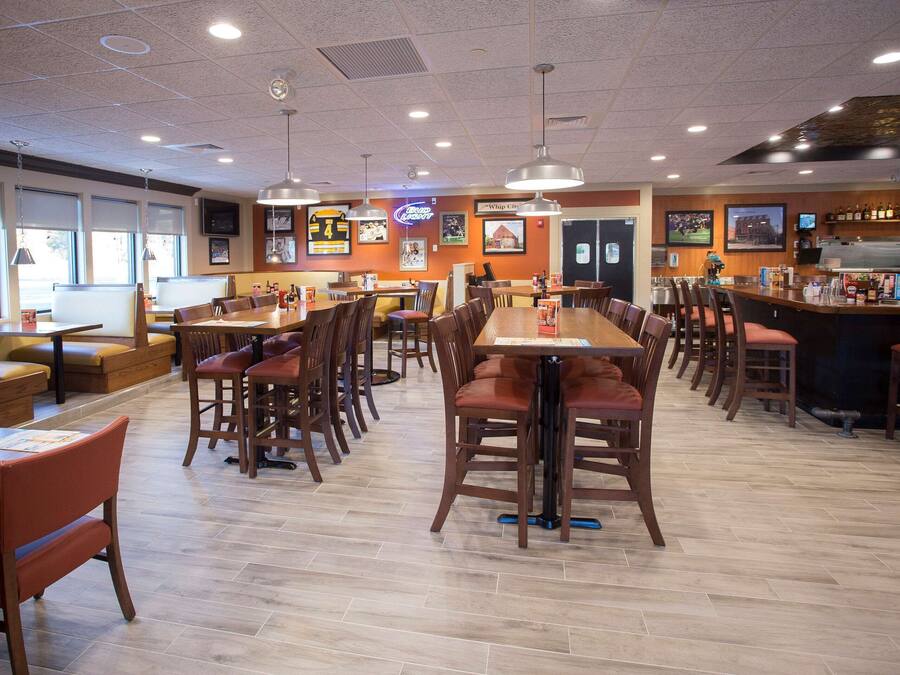 Un restaurante con varias mesas y cabinas para comer, una zona de bar y diferentes adornos en las paredes, incluyendo recuerdos deportivos.