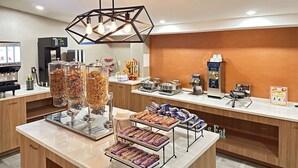 A hotel breakfast area with a self-serve station, including cereal, pastries, and beverages. - Clarion Inn Nashua (Nashua)