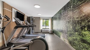 A gym with treadmills, a stationary bike, and a rowing machine. There is a large motivational poster on the wall and a window with a view of trees. - Clarion Inn Nashua (Nashua)