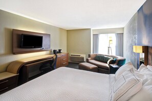 A hotel room with a large bed, a desk with a flat-screen TV, a sofa, and a lamp. - Courtyard By Marriott Cape Cod Hyannis (Hyannis)