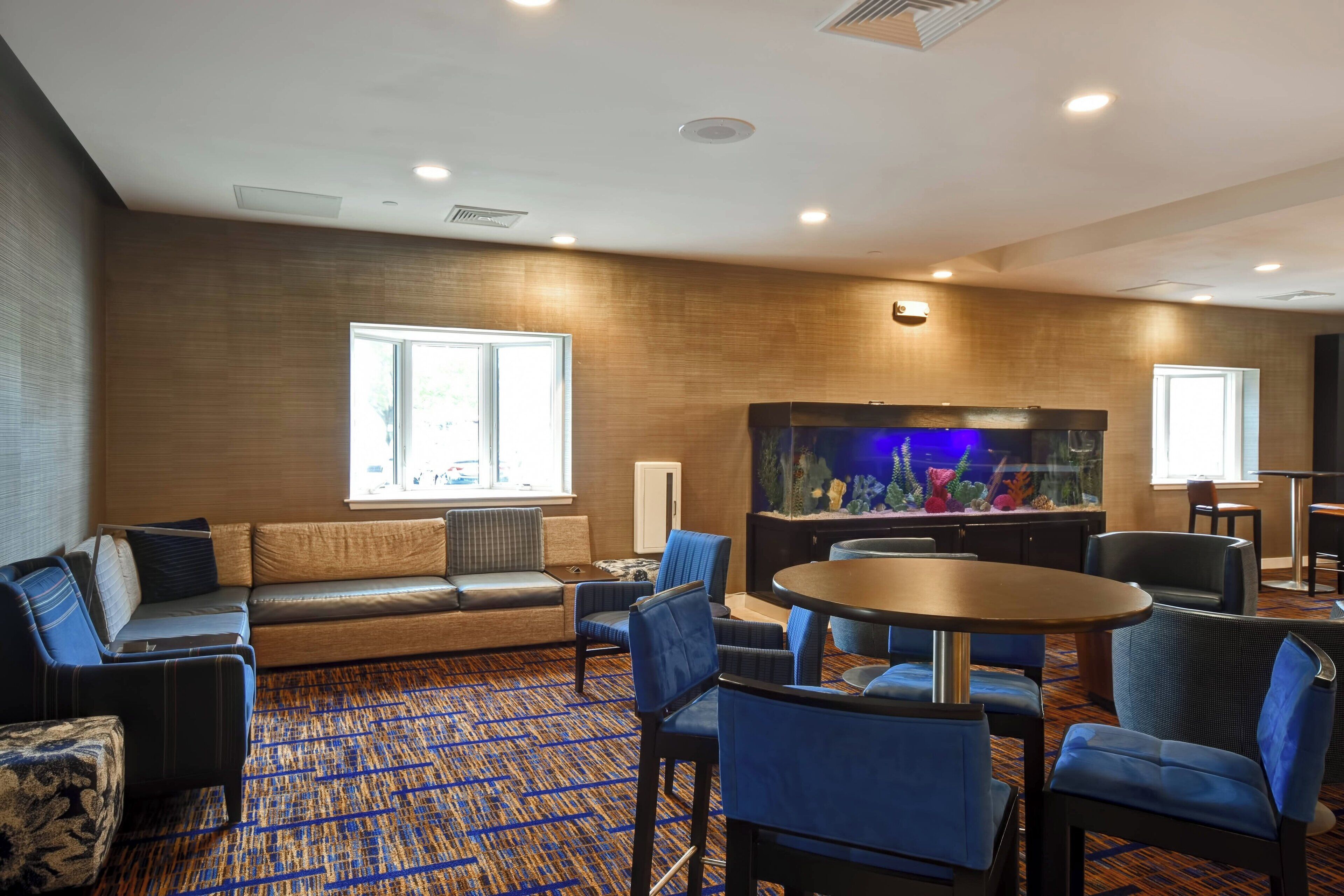 Hotelkamer met een groot aquarium, zithoek en een kamerbreed tapijt met dessin.