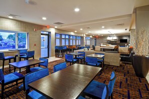 A hotel lobby with multiple seating areas, including tables and chairs, a reception desk, and a kitchen area. - Courtyard By Marriott Cape Cod Hyannis (Hyannis)