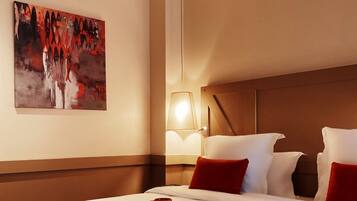 Ein Hotelzimmer mit einem großen Bett, einem Nachttisch mit Lampe und einem Bild an der Wand.