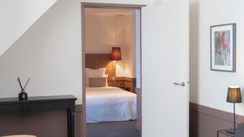 A hotel room with a bed, bedside lamp, and a small table with a candle.