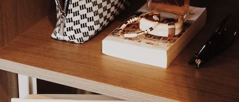 Une étagère en bois sur laquelle se trouvent un parfum Chanel, un sac à main à carreaux et un stylo noir.