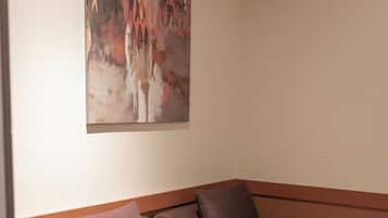 A room with a single bed, a painting on the wall, and a wooden headboard.