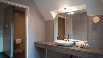 A modern bathroom with a large mirror, a vessel sink, and a walk-in shower.