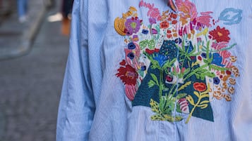 A person wearing a striped shirt with a colorful embroidered floral design.