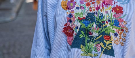 A person wearing a striped shirt with a colorful embroidered floral design.