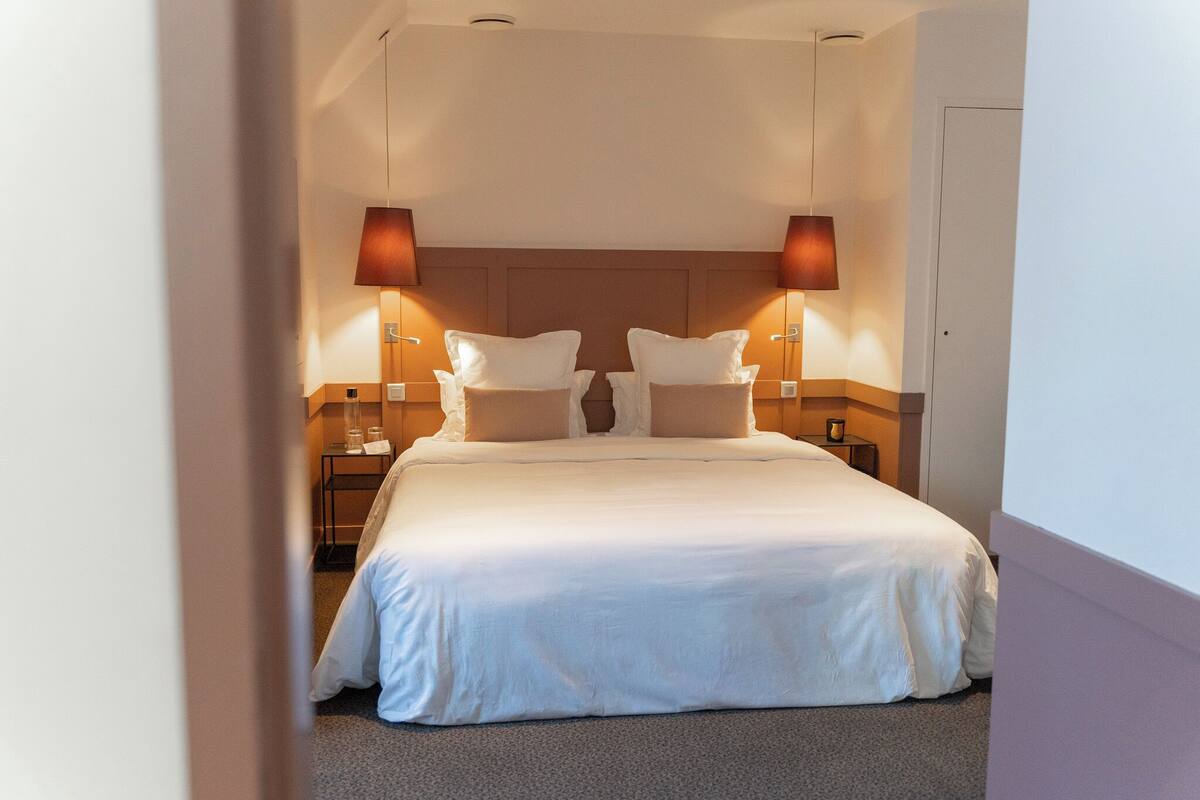 A neatly made double bed with two bedside tables, each with a lamp.