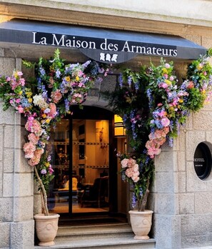 A hotel entrance with a sign reading 'La Maison des Armateurs' and a large floral archway. - La Maison des Armateurs (Saint-Malo)