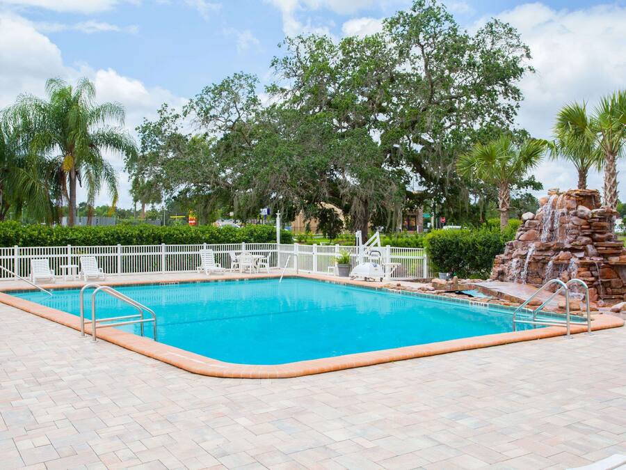 A rectangular swimming pool with a white deck and metal railings.