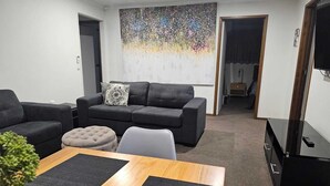 A living room with a grey sofa set, a coffee table, and a television.