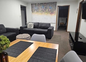 Una sala de estar con un sofá gris, una mesa de centro y un televisor.