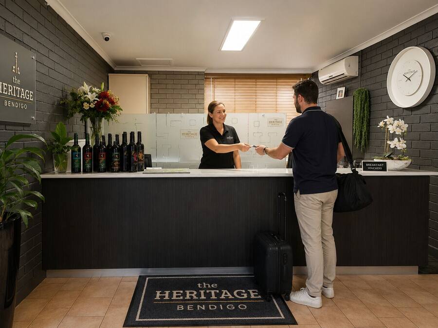 Zona de recepción de un hotel con un mostrador, un reloj y un cartel que indica los vales de desayuno.