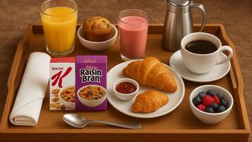 Ein Frühstücksbrett mit einem Muffin, einem Croissant, Saft, Kaffee, Müsli und frischen Beeren.
