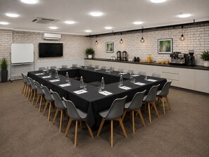 A conference room with a long table, chairs, a whiteboard, and a coffee station. - The Heritage Bendigo (Golden Square)
