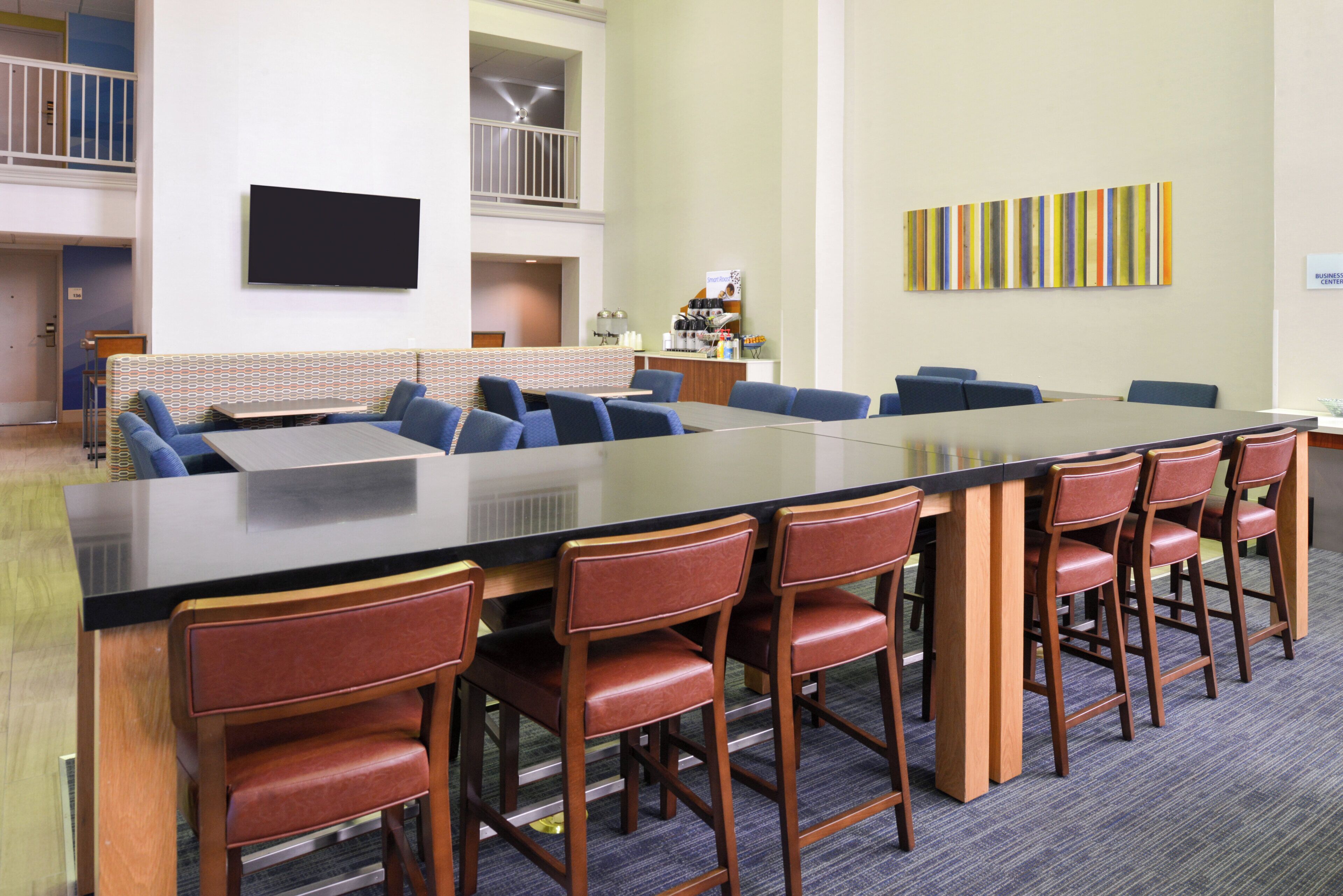 Une salle de conférence avec une longue table, des chaises bleues et un petit coin cuisine.