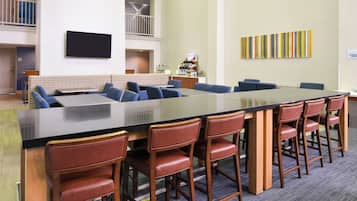 A conference room with a long table, blue chairs, and a small kitchenette area.