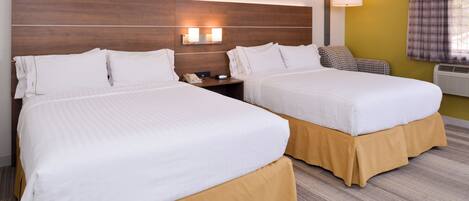 A hotel room with two beds, a nightstand, a lamp, and a window with curtains.