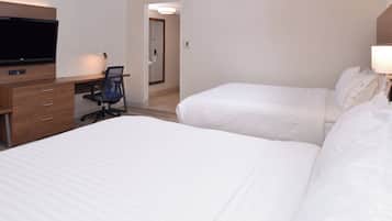 Een hotelkamer met twee bedden, een bureau met stoel, een televisie en een deur naar een andere kamer.