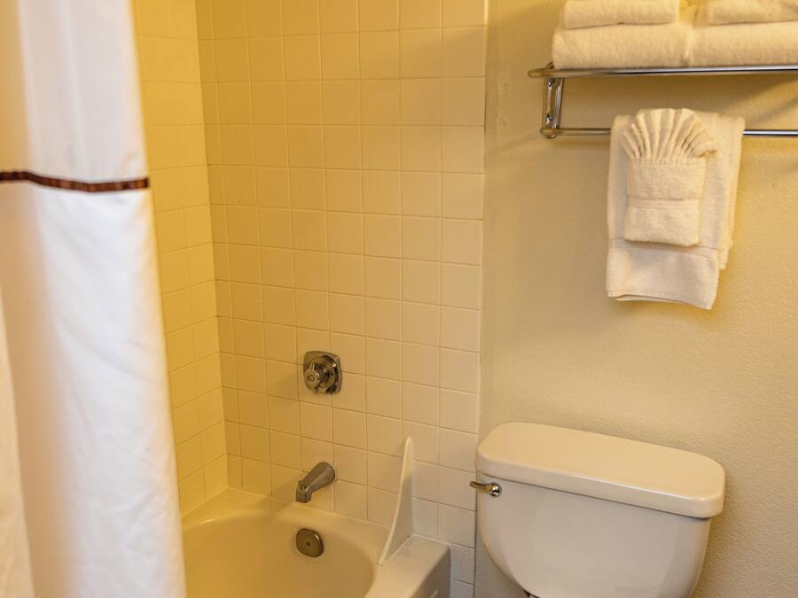A bathroom with a bathtub, toilet, and a towel rack with folded towels.