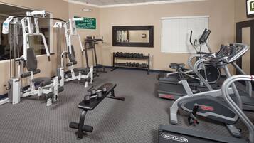 A gym with various exercise equipment including treadmills, dumbbells, and weight machines.