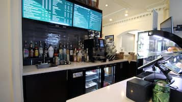 A coffee bar with a menu, a cash register, and a refrigerated display.