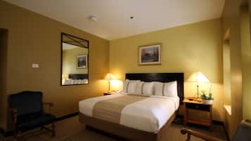 Una habitación de hotel con una cama grande, dos mesitas de noche con lámparas, una silla, un espejo y un cuadro en la pared.