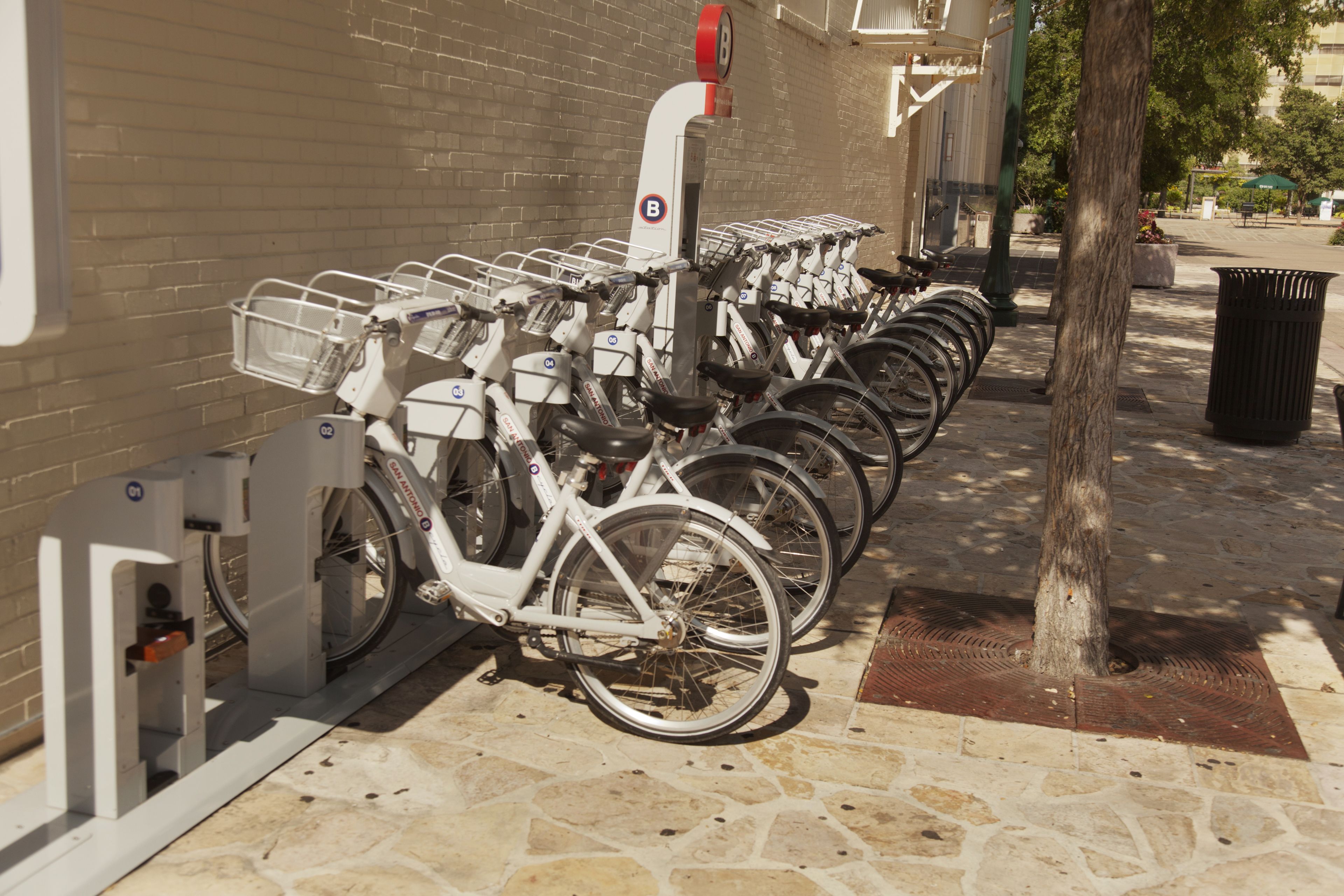 A row of bicycles parked next to a building with a brick wall.