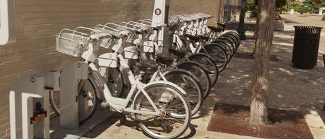 A row of bicycles parked next to a building with a brick wall.