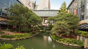A tranquil courtyard with a central water feature, surrounded by lush greenery and modern buildings. - Crockett Hotel (San Antonio)