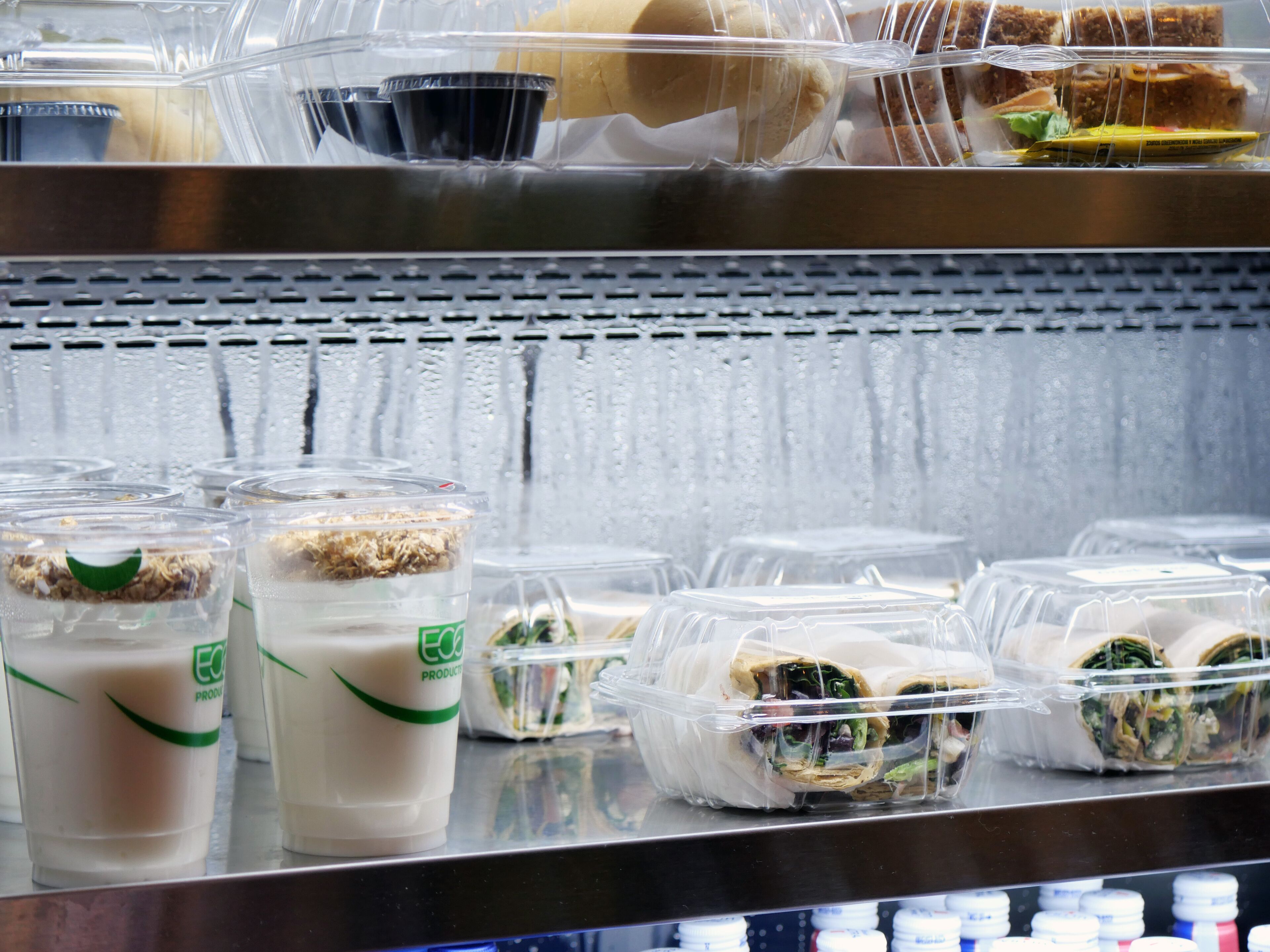Un refrigerador exhibe sándwiches y bebidas envasadas.