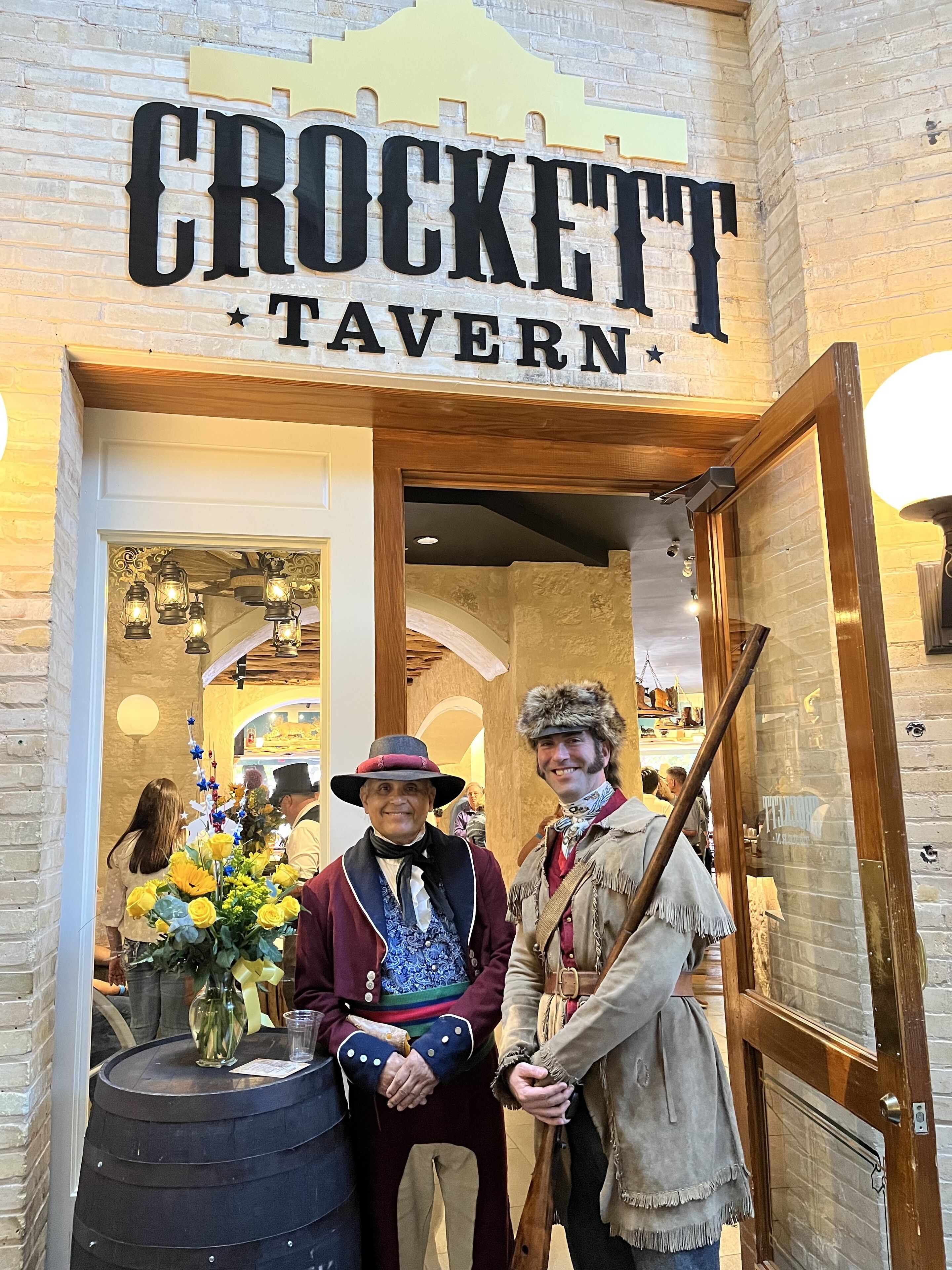 The exterior of CROCKETT TAVERN with a brick facade and a wooden door.