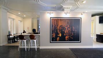 A modern interior with a large framed artwork on the wall, a bar area with stools, and a seating area with tables and chairs.