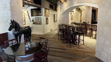 A restaurant with rustic decor, featuring wooden beams, a horse statue, and multiple dining tables and chairs.