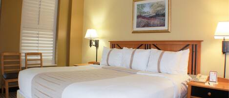 A hotel room with a large bed, two bedside tables, a chair, and a painting on the wall.