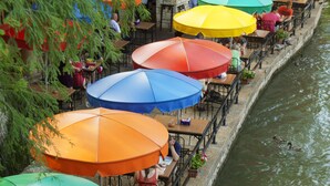 Outdoor dining tables with umbrellas along a canal. - Crockett Hotel (San Antonio)