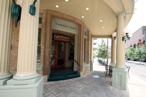 Entrada del Hotel Crockett con un cartel de café, grandes columnas y un paseo cubierto.