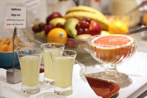 A table with a fruit bowl, a glass of ginger shot, and shot glasses. - Hotel Djingis Khan (Lund)